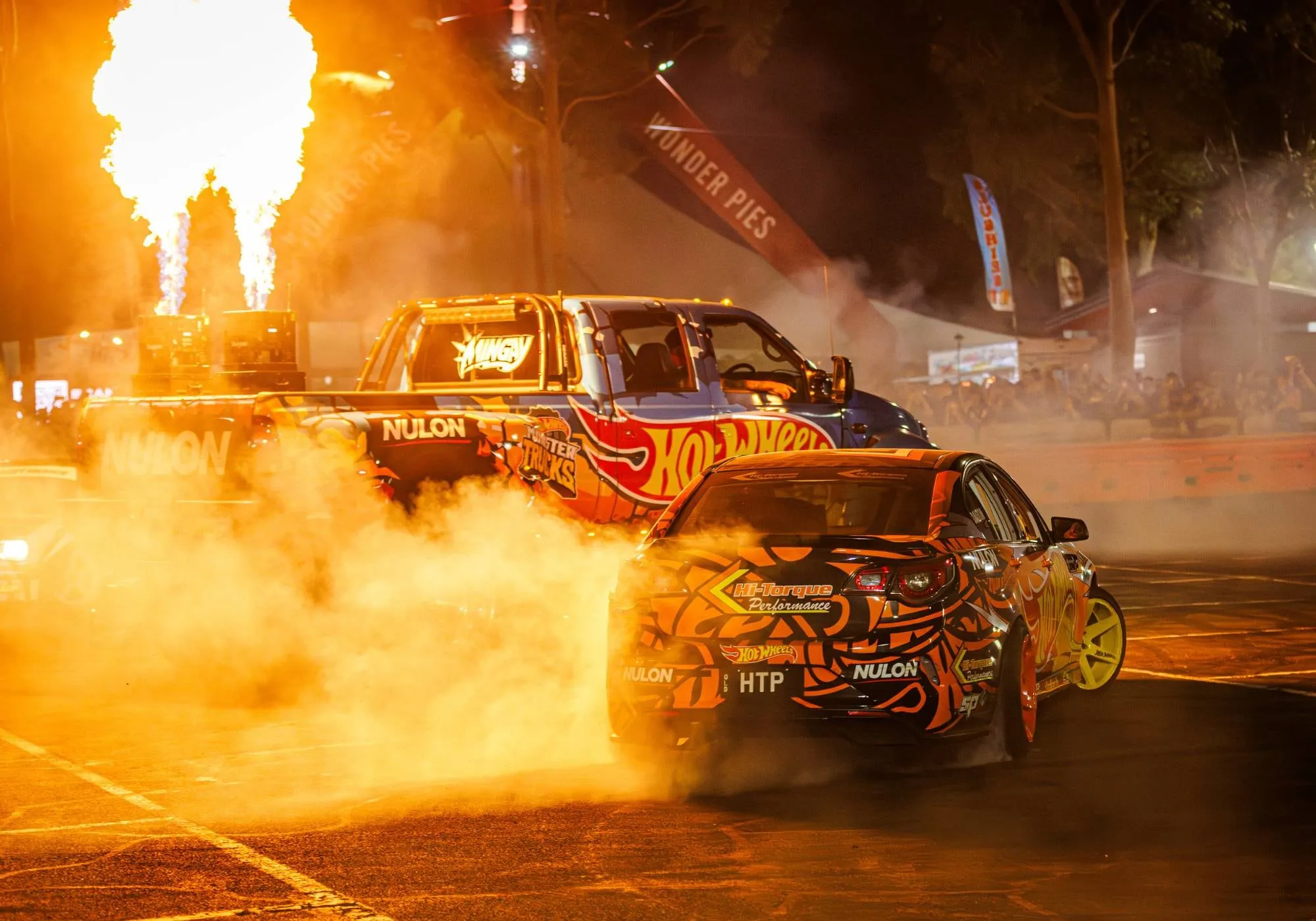 Hot Wheels stunt cars in a cloud of smoke with flame cannons firing at night