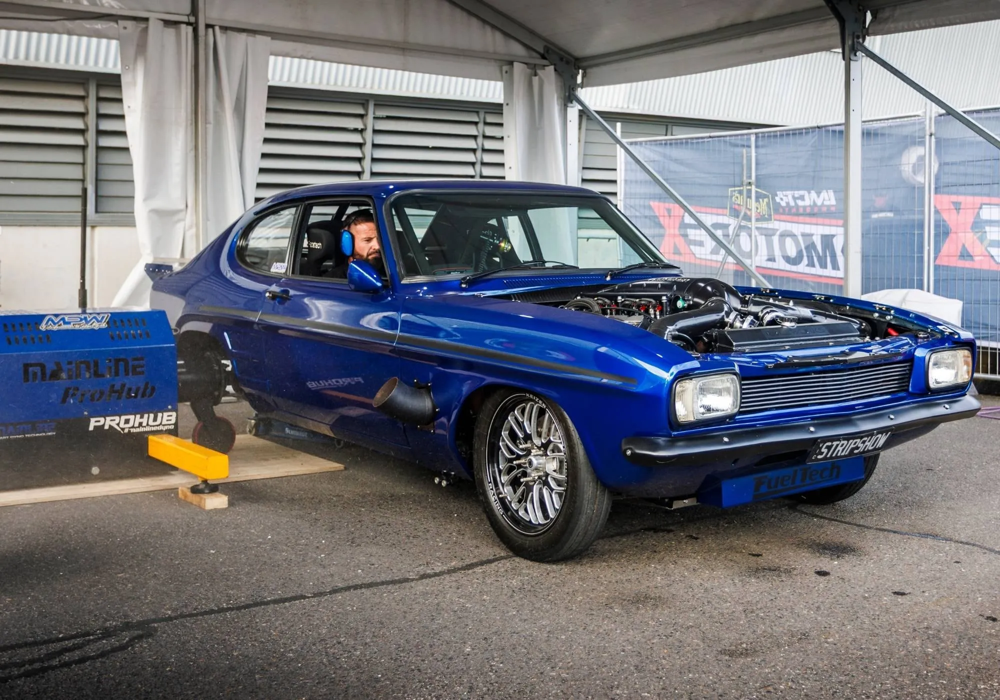 A blue Ford Capri strapped down on the Dyno World rollers