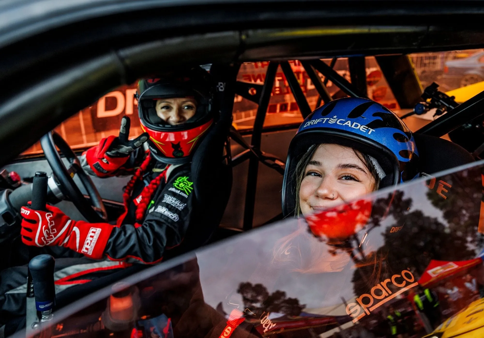 A driver and passenger grinning in a drift car