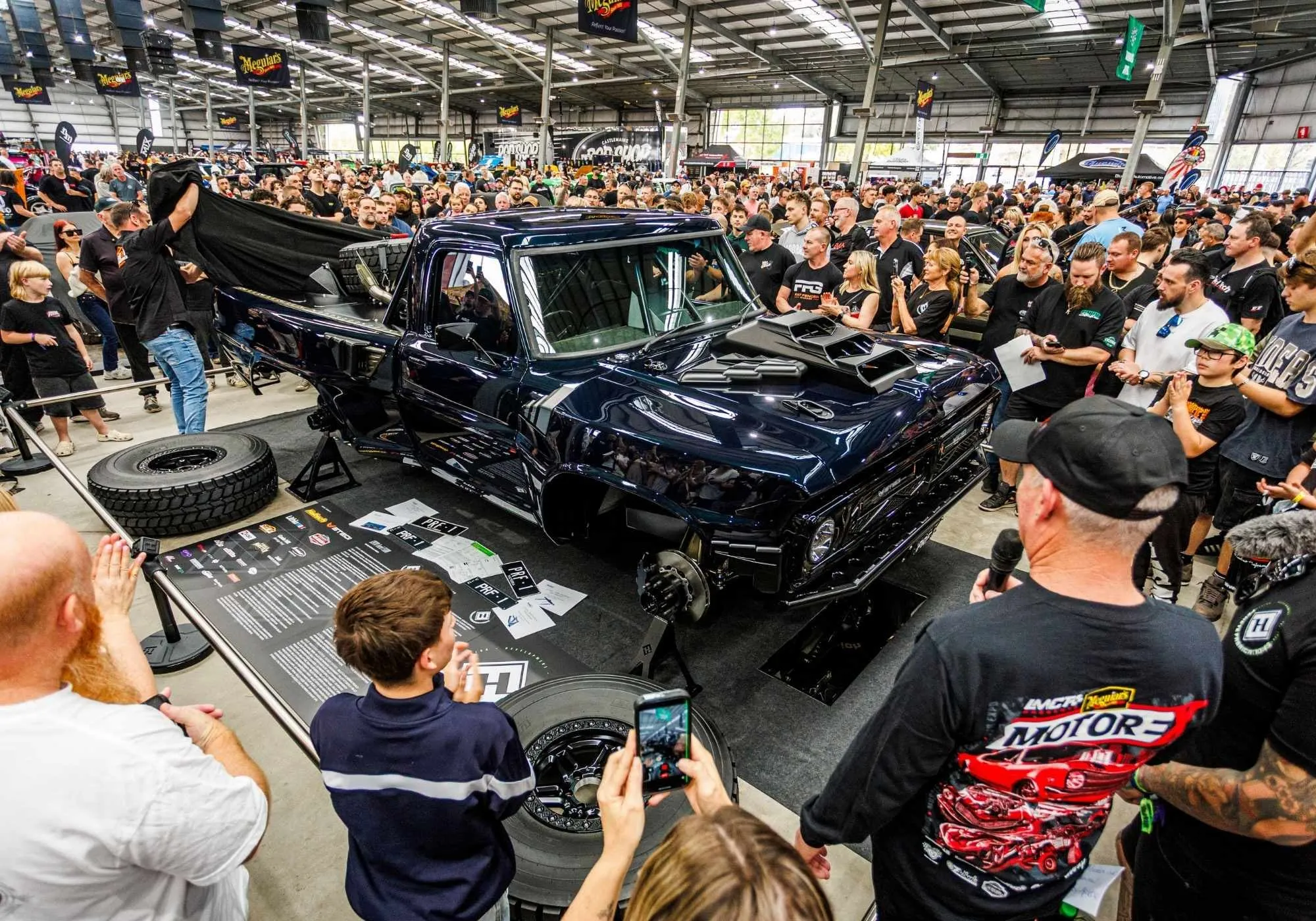 A crowd surrounds a black truck being unveiled in Meguiar’s Superstars World